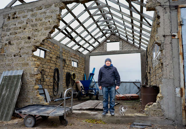 Viktor stands amidst the ruins of his farm building.